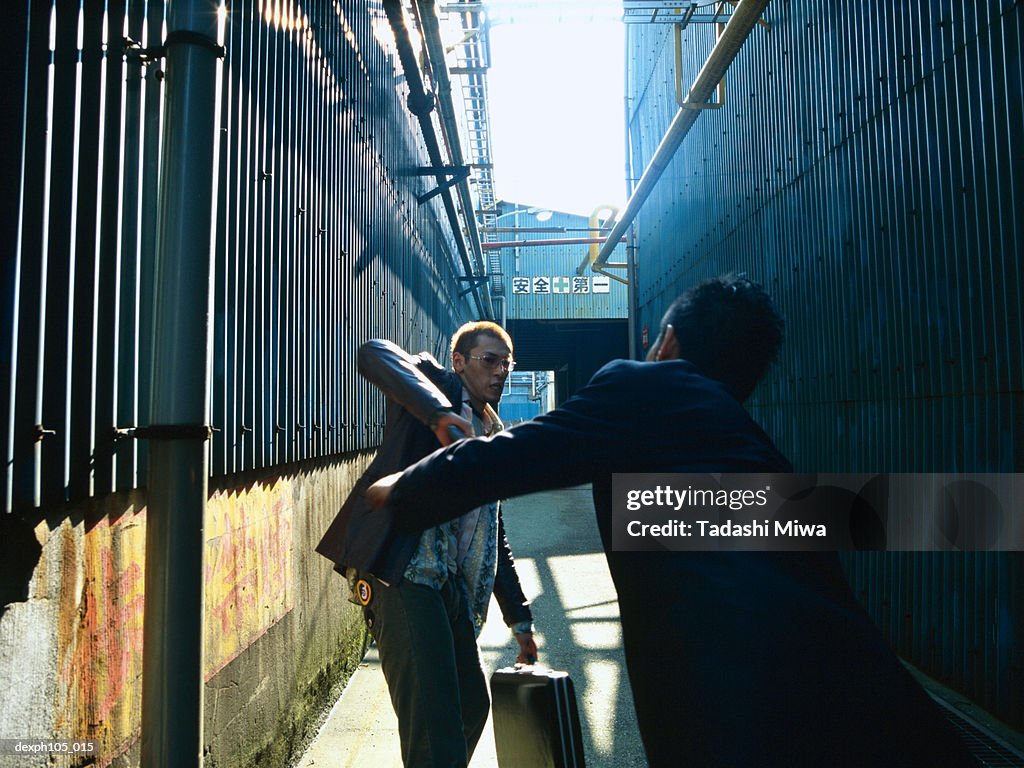 Two men struggling  in a small alley