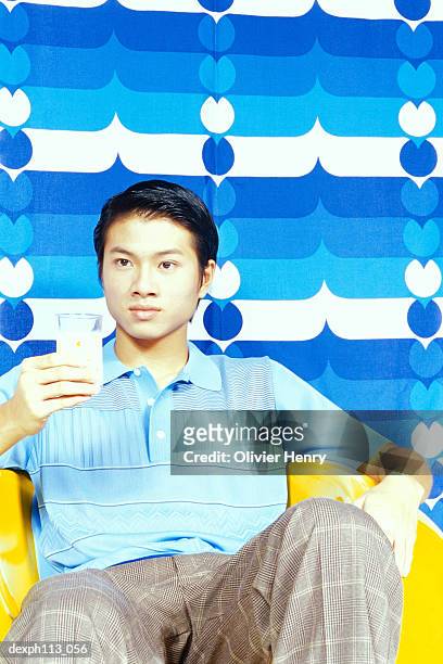 man sitting on yellow ball chair holding a glass of milk - ball chair stock pictures, royalty-free photos & images