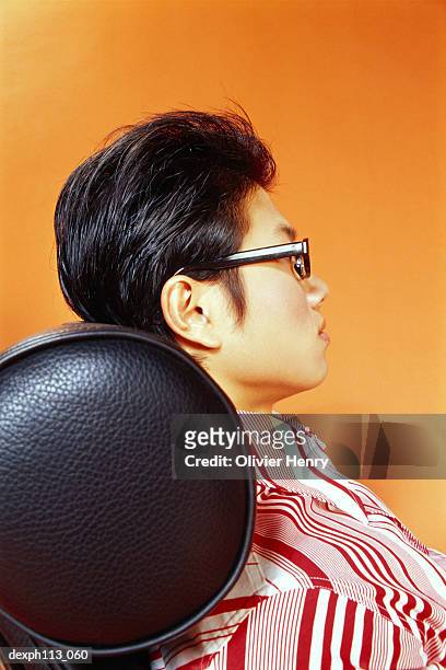 young man relaxing on leather couch, profile - repose tête photos et images de collection