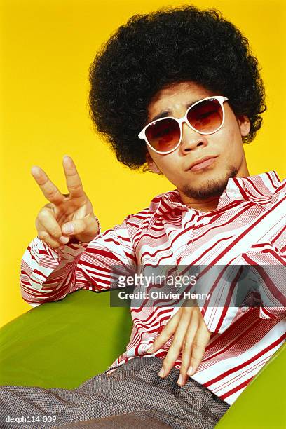 young asian male with afro hair sitting with victory pose - henry stockfoto's en -beelden