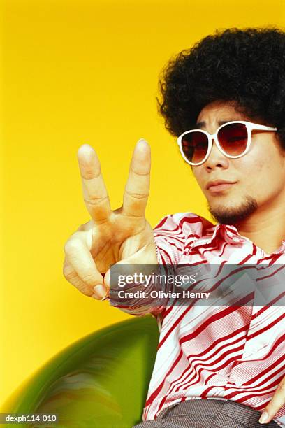 young asian male with afro hair sitting with victory pose - henry stock pictures, royalty-free photos & images