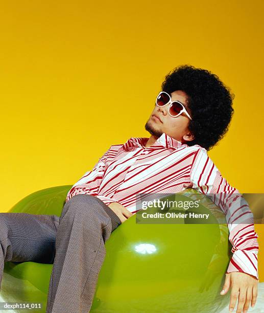 young asian male with afro hair sitting on ball chair - ball chair stock pictures, royalty-free photos & images