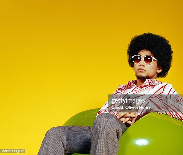 young asian male with afro hair sitting on ball chair - henry stockfoto's en -beelden