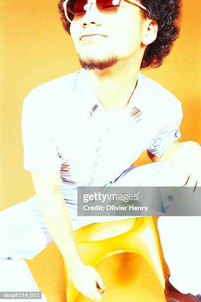 young asian male with afro hair sitting on ball chair - henry stock pictures, royalty-free photos & images