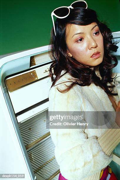 young woman standing by open refrigerator - henry stockfoto's en -beelden