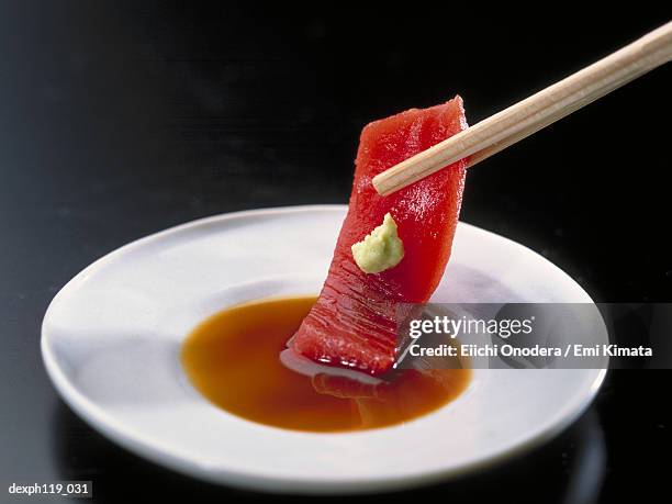 dipping a slice of raw fish in soya sauce - wasabi sauce stock pictures, royalty-free photos & images
