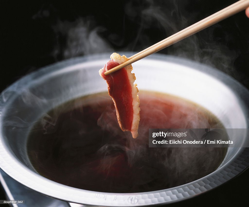 Dipping a slice of beef in hot soup