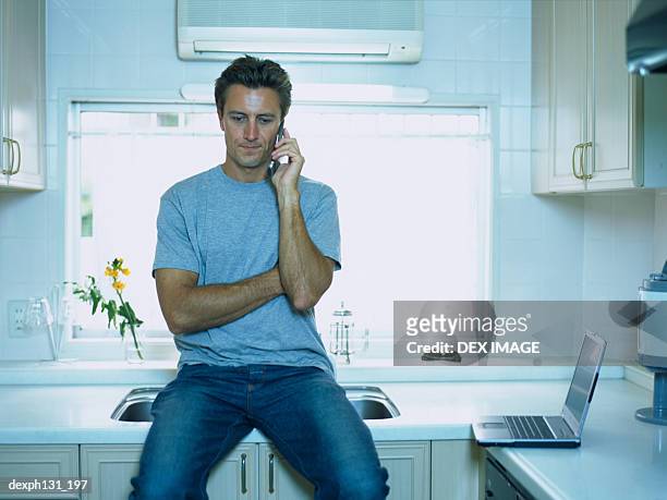 man sitting on a basin counter with a mobile phone - basin ストックフォトと画像