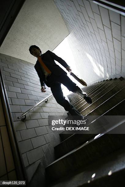 low angle view of a young businessman coming down a flight of stairs - people coming of age purify with icy water in tokyo stockfoto's en -beelden