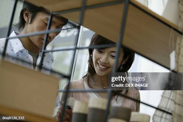 young couple looking at items for sale on a shelf - commercial event stockfoto's en -beelden