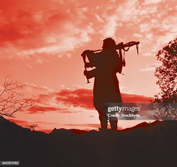 silhouette of a man playing bagpipes - dudelsack stock-fotos und bilder
