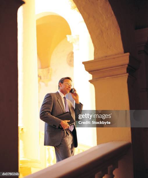 man standing in alcove, talking on cordless phone - alcove stock pictures, royalty-free photos & images