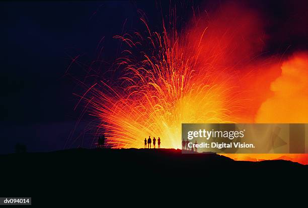 people standing on the edge of an erupting crater - distant fire stock pictures, royalty-free photos & images