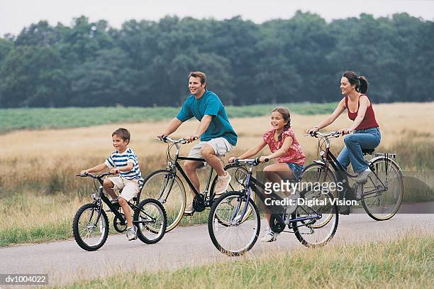 family cycling on a country road - two kids with cycle imagens e fotografias de stock
