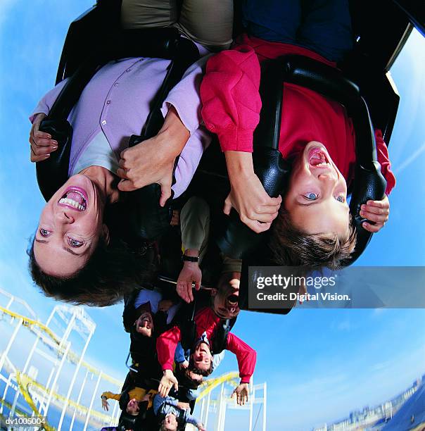 mother and son upside down on a roller coaster - rollercoaster stock-fotos und bilder