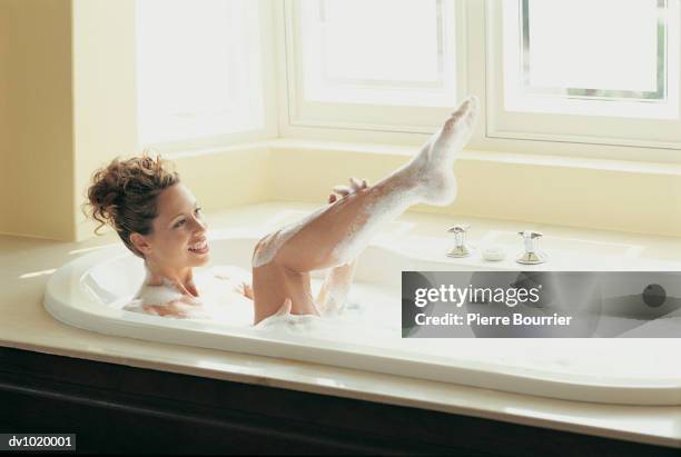 young woman lifting her leg in the bath - pierre brunet stock pictures, royalty-free photos & images