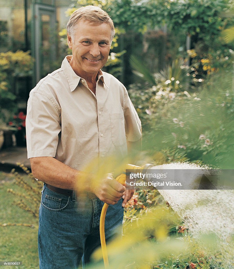 Portrait Of Mature Man Watering His Garden
