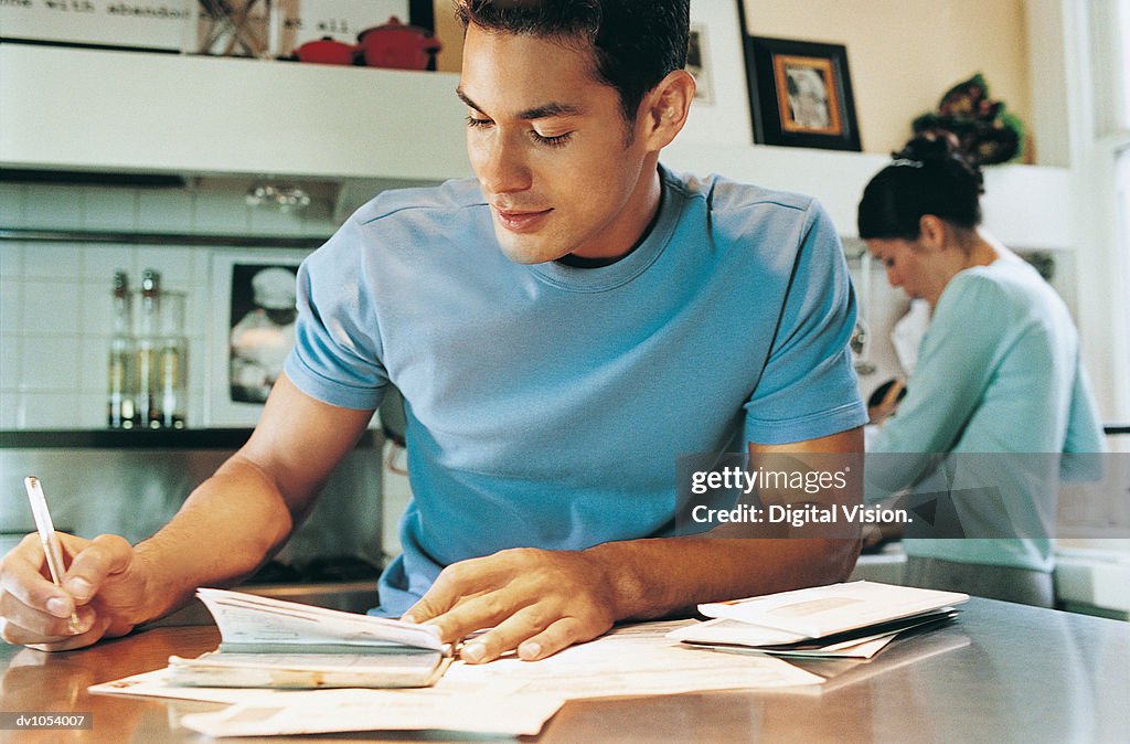 Man Writing in a Diary, Woman in the Background