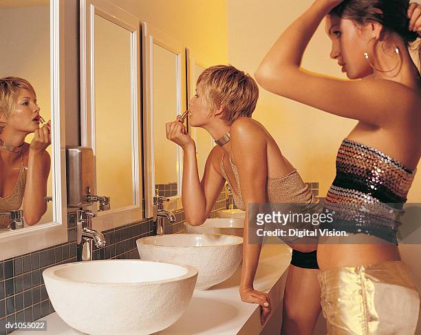 two young women looking in the mirror in a nightclub toilet - 女性用トイレ ストックフォトと画像