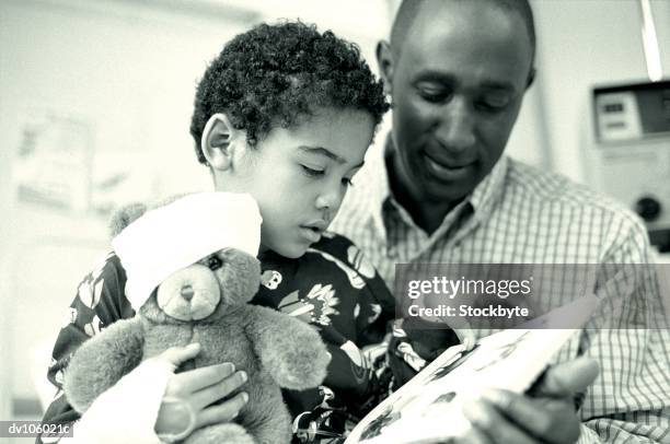 father and child looking at book - bedtime stories stock-fotos und bilder