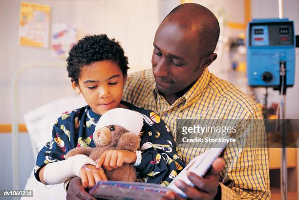 father and child looking at book - bedtime stories stock-fotos und bilder