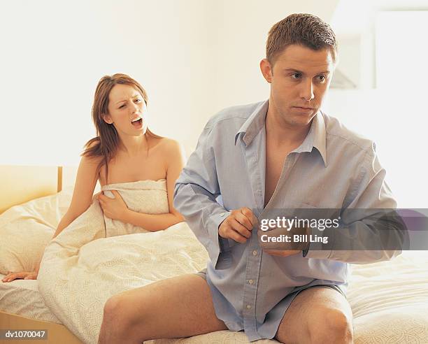 woman arguing with man as he gets dressed - girlfriend leaving stock pictures, royalty-free photos & images