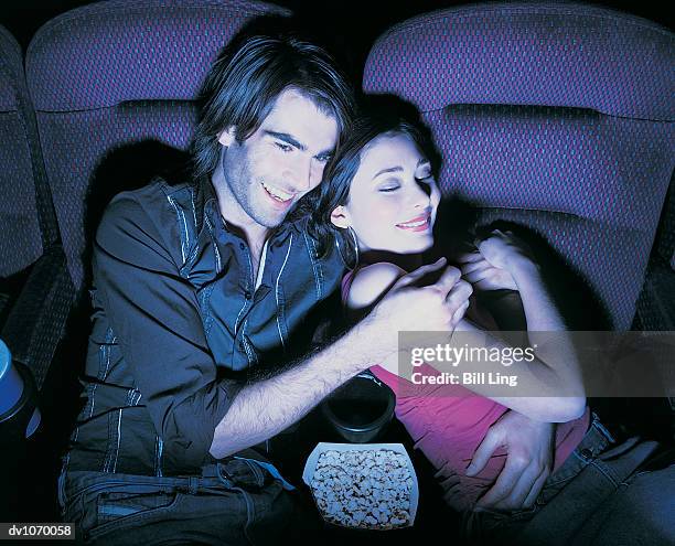 man with his arm around a woman at the cinema - proceso cruzado fotografías e imágenes de stock