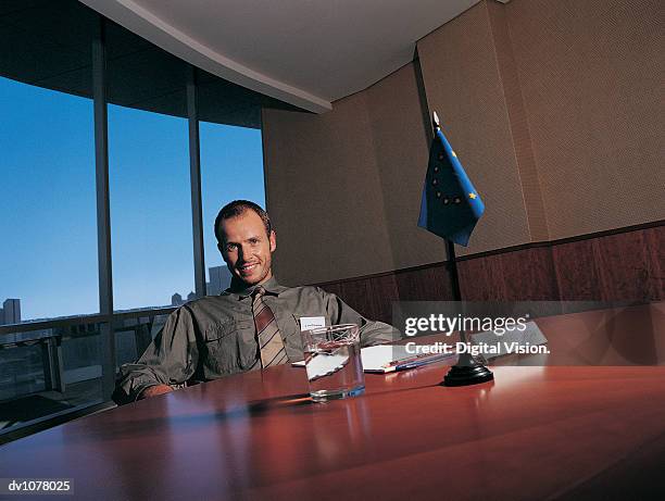 portrait of a businessman sitting at a conference table by a european union flag - upper midtown manhattan stock pictures, royalty-free photos & images