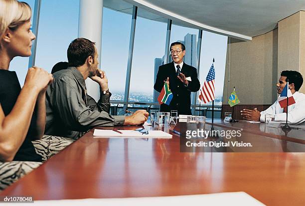 mature businessman standing at a conference table with other business executives applauding him - upper midtown manhattan stock pictures, royalty-free photos & images