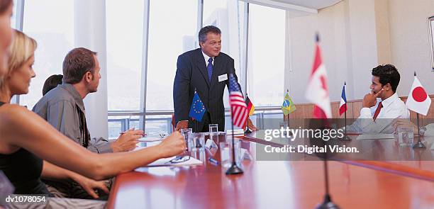 businessman giving a presentation in a conference room to other business executives - united nations building flags stock pictures, royalty-free photos & images