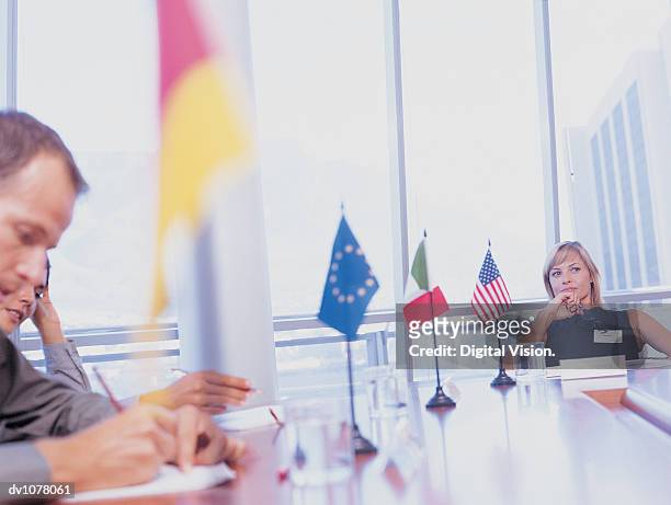 contemplative businesswoman sitting at the end of a conference table in a meeting - key speakers at the international economic forum of the americas conference of montreal stockfoto's en -beelden