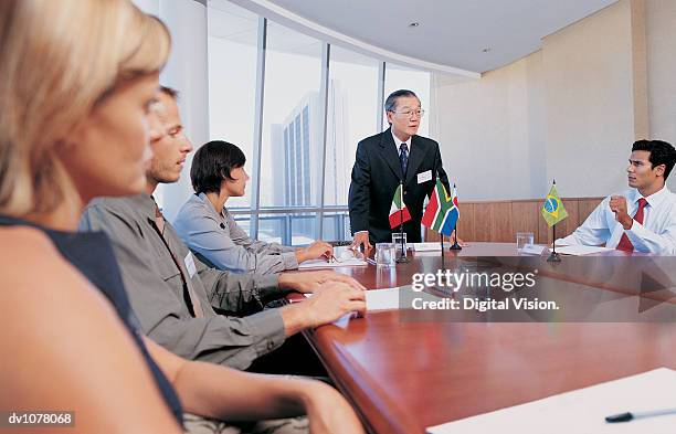 five business executives around a conference table having a meeting - south american flags stockfoto's en -beelden