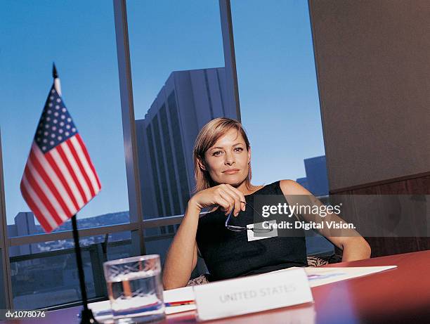 portrait of a businesswoman sitting at a conference table by the stars and stripes - key speakers at the international economic forum of the americas conference of montreal stockfoto's en -beelden