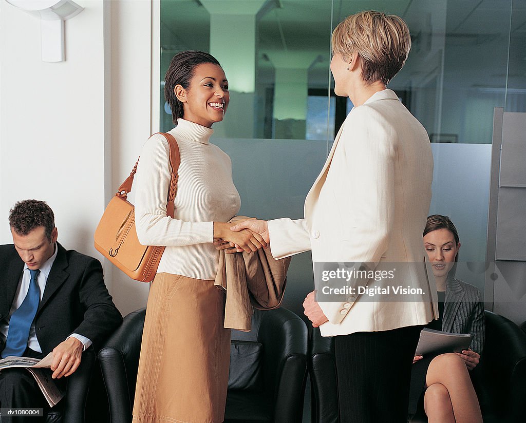 Businesswoman Greeting a Young, Female Interviewee in an Office