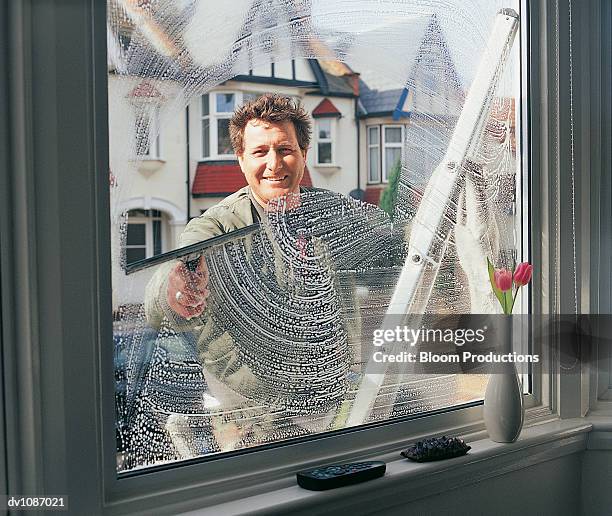 portrait of a window cleaner looking through and cleaning a window - trasa bildbanksfoton och bilder