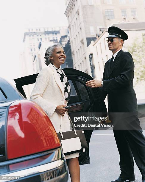 Mature Chauffeur Holding The Door Of A Car Open For A Female Ceo Manhattan New York Usa, Foto de stock