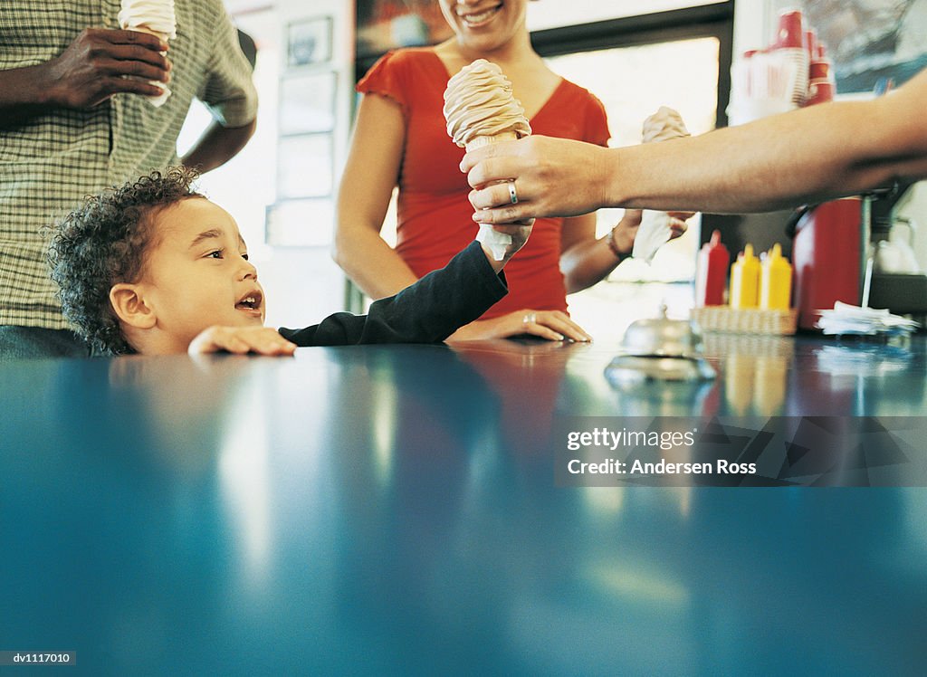 Child With His Parents Being Given an Ice Cream in a Cafe