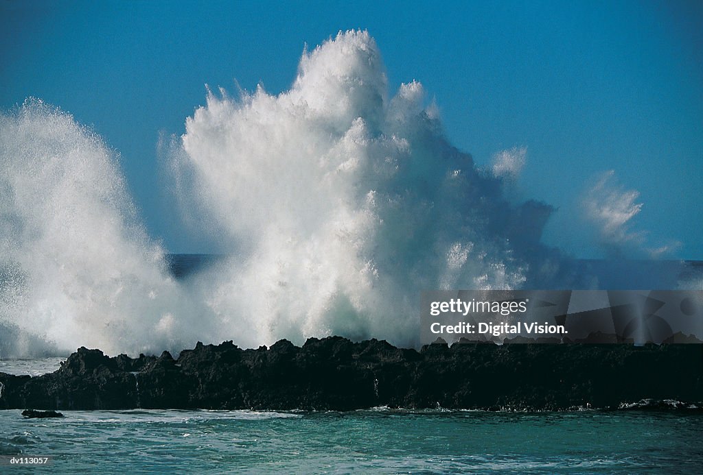 Waves crashing on rocks, sending up spray