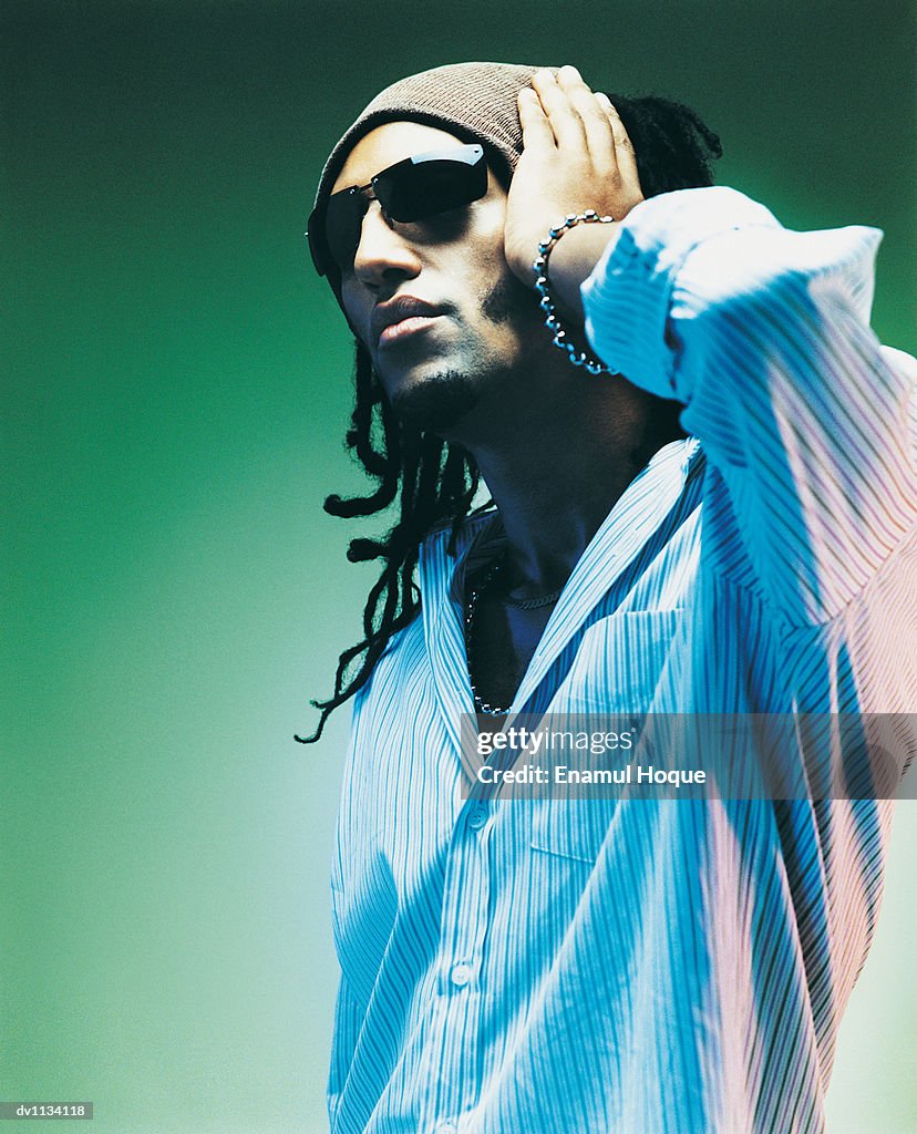 Portrait of a Young Man Wearing Sunglasses and a Woollen Hat With His Hand on His Head
