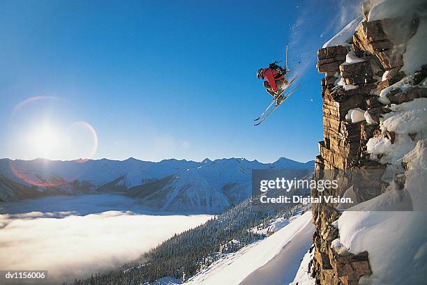 skier jumping mid air off a steep rock face off piste - face off sports play - fotografias e filmes do acervo