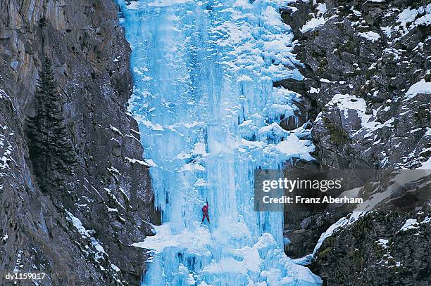 person climbing up an ice-covered cliff - franz aberham 個照片及圖片檔