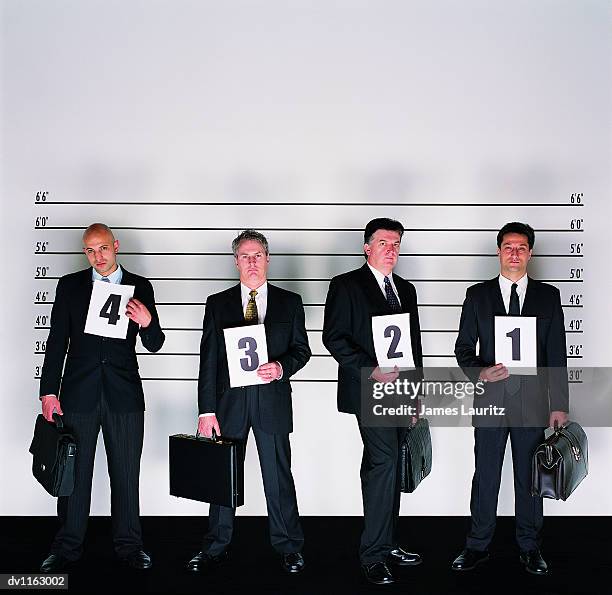 group of serious businessmen standing holding briefcases and placards in a police line-up - police line up stock-fotos und bilder
