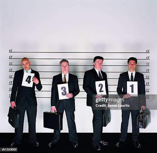 group of serious businessmen standing holding briefcases and placards in a police line-up - lineup fotografías e imágenes de stock