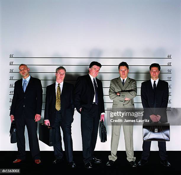 group of serious businessmen standing holding briefcases in a police line-up and a man with his arms crossed - police line up stock-fotos und bilder