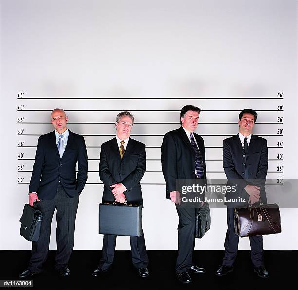 group of serious businessmen standing holding briefcases in a police line-up - lineup fotografías e imágenes de stock