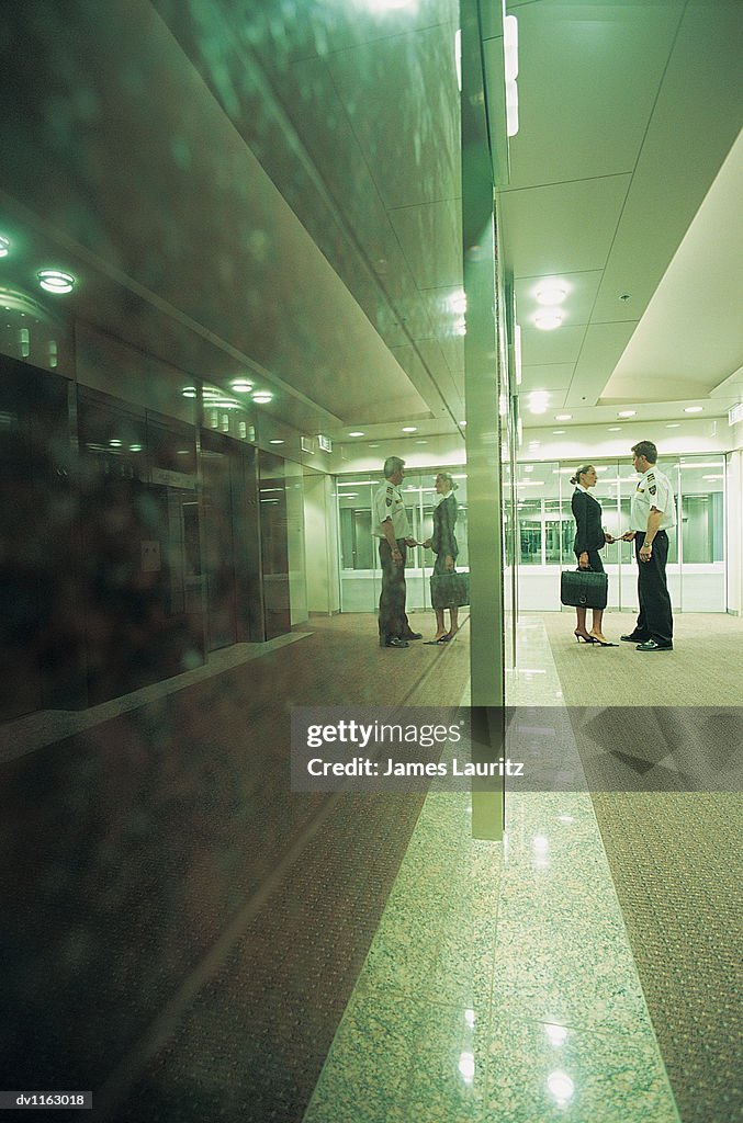 Suspicious Businesswoman and Security Guard Standing in a Hotel Lobby
