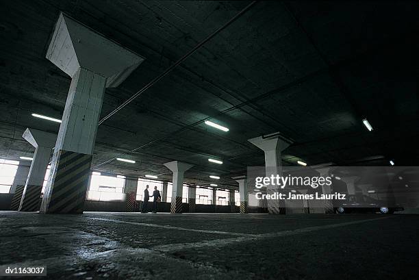 distant view of suspicious businessmen standing in a car park shaking hands - distant imagens e fotografias de stock