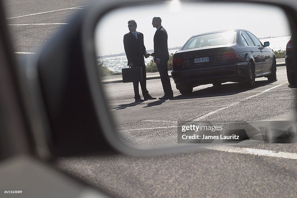 Suspicious Businessmen in a Carpark Giving and Recieving a Bribe