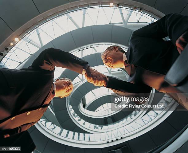 below view of businessmen shaking hands and a view of a spiral gangway - spiral foto e immagini stock