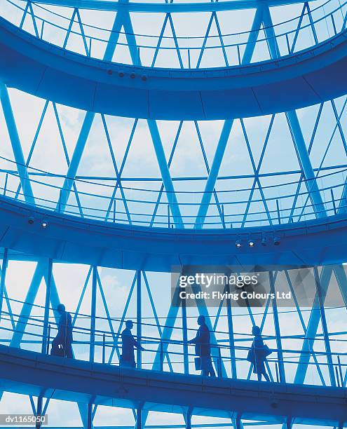 four business executives walking at the bottom of a spiral staircase - spiral foto e immagini stock